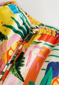 Farebná látka s kvetinovým vzorom a prešívanou textúrou. Obsahuje žiarivé odtiene ako žltá, oranžová a ružová, s elastickým pásom a detailmi prešívania.