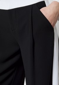 Svartvita byxor med strukturerad tyg, med sidoficka och vit detalj vid sömmen. Skräddarsydd design med en smidig finish.