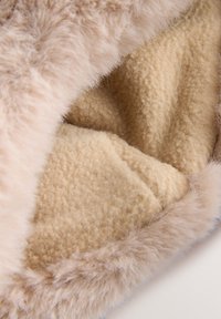 Jaukus smėlio spalvos dirbtinio kailio pamušalas su minkšta, purus tekstūra. Pamušalas pasižymi švelniu, šviesiai smėlio atspalvio paviršiumi, kuris sustiprina šilumą ir komfortą.