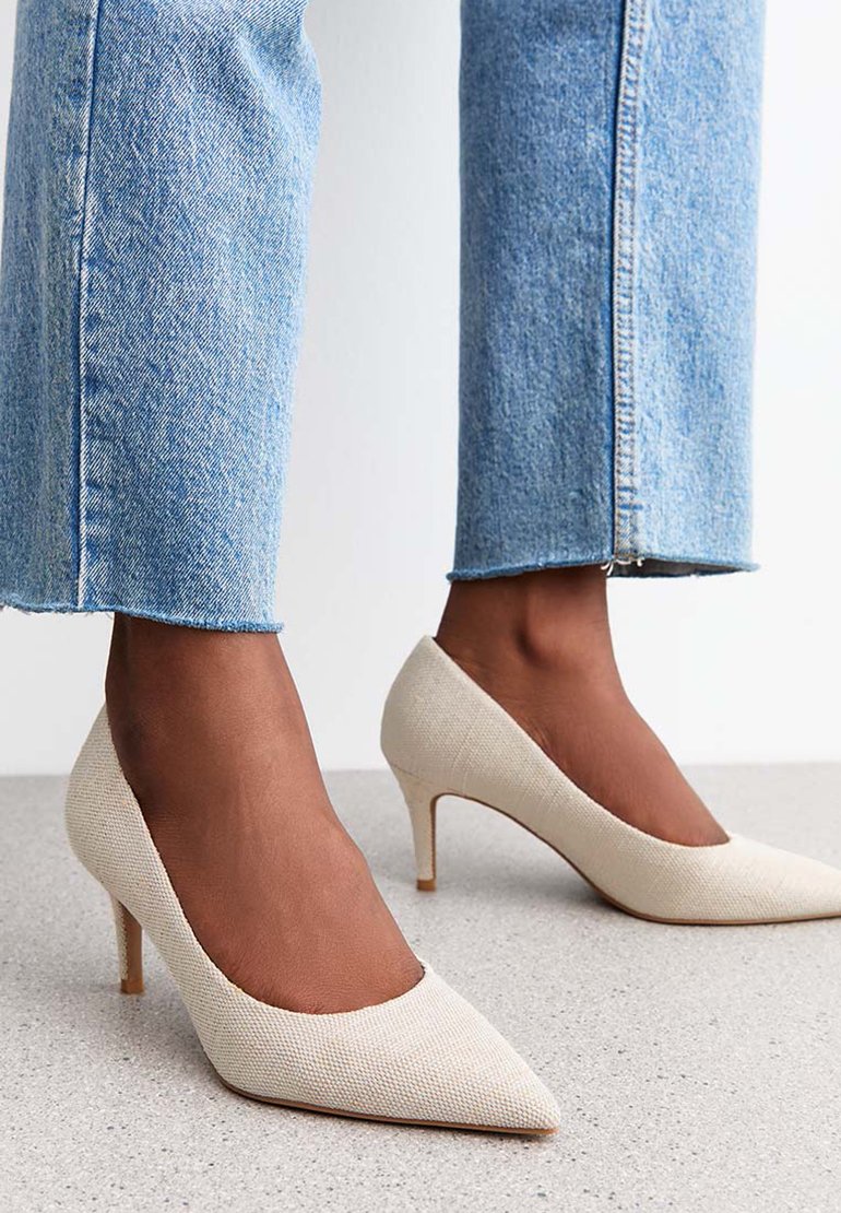 Décolleté beige in tessuto testurizzato, con punta appuntita e tacco sottile, abbinati a jeans cropped blu chiaro.
