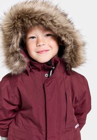 Bordeauxfärgad parkas med faux fur-huva, dragkedja och knappstängning samt sidofickor. Texturerad tyg med en jämn finish, lämplig för kallt väder.