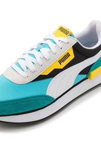 Puma Sneaker aus türkisfarbenem Stoff, mit weißen Schnürsenkeln, schwarzen und gelben Akzenten, strukturierten Oberflächen und einer kontrastierenden weißen Zwischensohle.