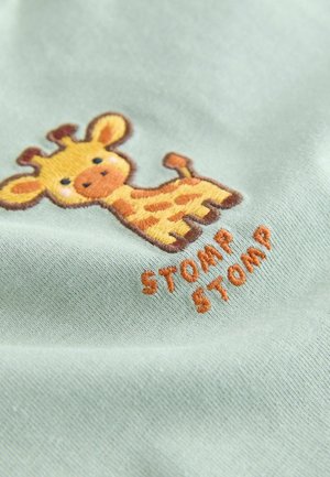 Material verde deschis cu o girafă brodată în galben și maro, cu textul „STOMP STOMP” în portocaliu dedesubt. Textură moale.