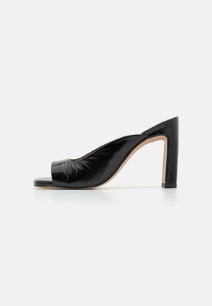 Mule à bout ouvert en cuir verni noir avec un talon épais haut et une semelle lisse couleur tan sur fond blanc.