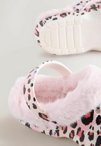 Leopardprint træskor med et pink, fluffy interiør og en hvid rem. Gummisål med struktureret mønster for godt greb. Blødt og varmt design.