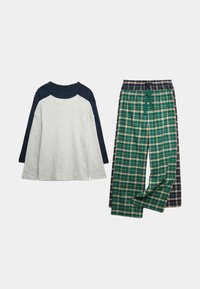 Szara bluzka z długim rękawem w granatowe akcenty obok zielonych spodni w kratkę z beżowymi tonami. Oba elementy charakteryzują się luźnym krojem i miękkim materiałem.