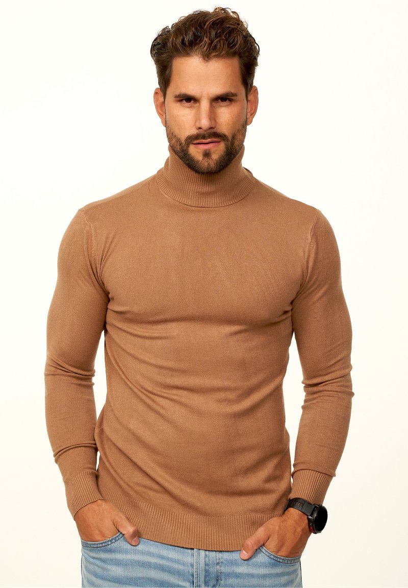 Brauner Hochkragenpullover aus weichem Material, figurbetontes Design mit langen Ärmeln und gerippten Bündchen, getragen über hellblauen Jeans.