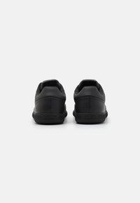 Svarte lær sneakers med rund tå, teksturerte detaljer, polstret krage og mønstredd gummisåle. Merking er synlig på hælen.
