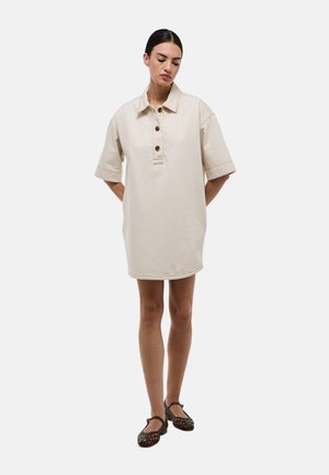 Robe chemise en coton beige avec un col, des manches courtes, des boutons sur l'avant et des poches latérales. Ourlet droit et coupe décontractée.