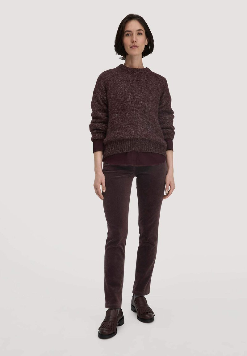 Bordeaux gebreide trui met een ronde hals, gecombineerd met bijpassende fluwelen broeken. Footwear is donkerbruine instappers met franjes.