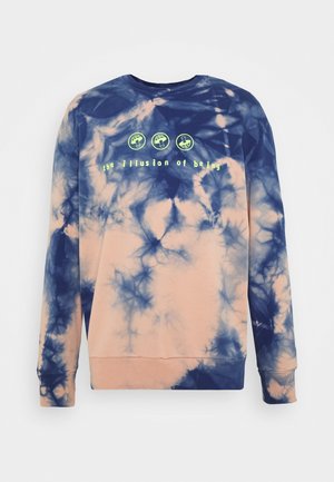 Tie-dye trui in marineblauw en perzik met groene paddenstoel-iconen boven de tekst "the illusion of being" op de voorkant, lange mouwen, ronde hals.