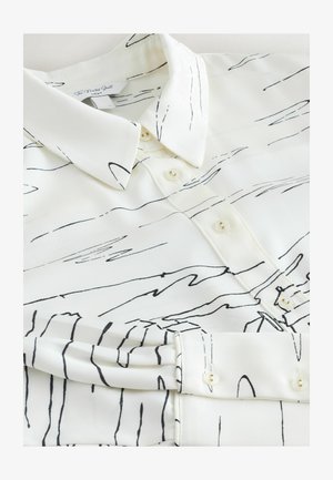 Vit skjorta med svart linjeteckning, med krage och knäppning framtill. Slät textur, subtil glans och långa ärmar med knappmanschetter.