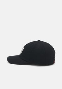 Casquette de baseball noire avec visière courbée, en tissu, dotée d'une étiquette blanche à l'avant, de six œillets de ventilation et d'une sangle arrière ajustable.