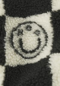 Tela de forro de cuadros blancos y negros con un patrón de caras sonrientes circulares tejido en la textura.