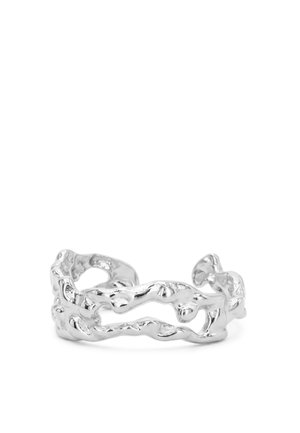 Anillo abierto de plata con un diseño orgánico, ondulado y texturizado que forma formas irregulares interconectadas.