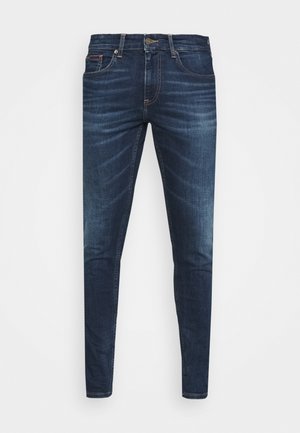 Dark blue denim jeans with a slim fit, subtle fade, five pockets, and a metal button closure. Stitched accents in contrasting color.