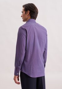 Camicia viola con un piccolo motivo circolare, maniche lunghe e colletto classico. Tessuto morbido con una texture liscia e orlo leggermente curvato.
