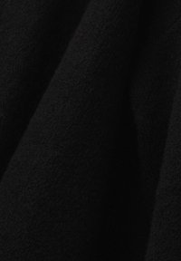 Tissu noir avec une surface douce et texturée ainsi que des plis subtils créant des ombres et des reflets délicats.