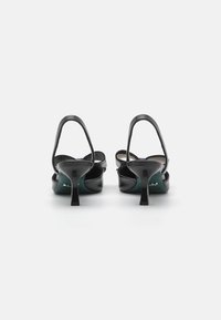Black high-heeled sandals with a sleek leather design, open back, and thin straps. Textured interior and a contrasting teal sole detail.