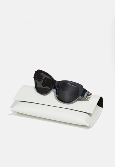 Occhiali da sole con motivo nero e blu, finitura lucida, custoditi in un'elegante custodia bianca con chiusura a pattina e bordo nero a contrasto.