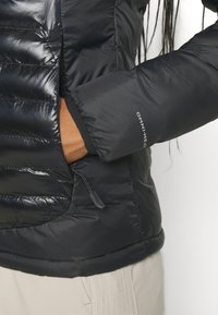 Giacca nera isolante con design trapuntato, polsini elasticizzati e tasca con zip con regolazione a cordino all'orlo.