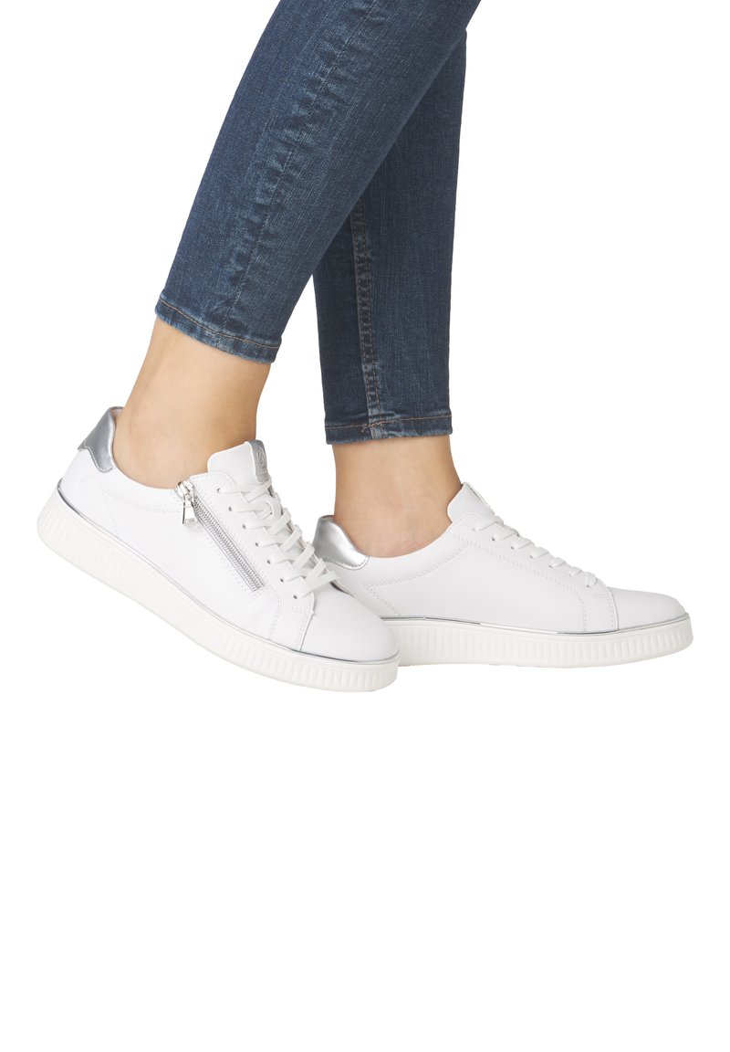 Baskets blanches avec un accent argenté au talon, dotées d'une fermeture éclair sur le côté, d'une semelle texturée, d'un design à lacets et d'un upper en cuir lisse.