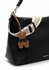 Sort tekstureret læderhåndtaske med en aftagelig stribet rem og et bamseformet mærkat med detaljer af en butterfly.