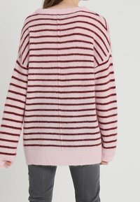 Růžový a mahagonový pruhovaný oversized svetr z měkkého, chlupatého materiálu; má dlouhé rukávy, volný střih a žebrovaný lem.
