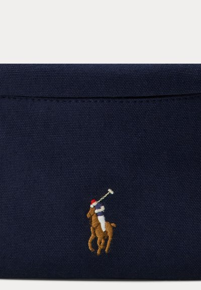 Marineblaue Canvas-Tasche mit einem braunen, bestickten Polo-Spieler zu Pferd, versehen mit weißen und roten Akzenten sowie detaillierten Stichen.