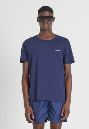 Camiseta de manga corta en color azul marino hecha de una tela suave, con un cuello redondo y un pequeño parche de logo en el lado izquierdo del pecho.