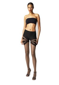 Sort bandeau top, højtaljede shorts med gennemsigtige paneler og gennemsigtige strømpebukser. Model iført åbne hæle. Rent, minimalistisk design.