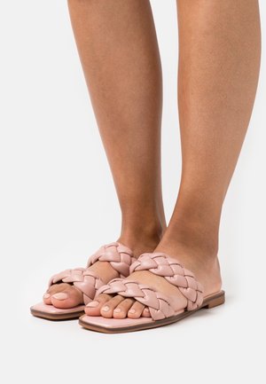 Ciabatte intrecciate in morbido cuoio rosa con suola piatta, caratterizzate da una finitura liscia e un design aperto sui piedi.