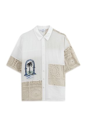 Bílé tričko s krátkým rukávem, které má texturované krajkové panely v béžové barvě a vyšívaný oblouk a vzor palmy na přední straně. Zapínání na knoflíky.