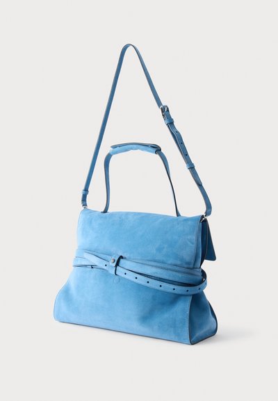 Sac à main en daim bleu clair avec deux sangles, dont une longue bandoulière réglable et une poignée plus courte, présenté sur un fond uni.