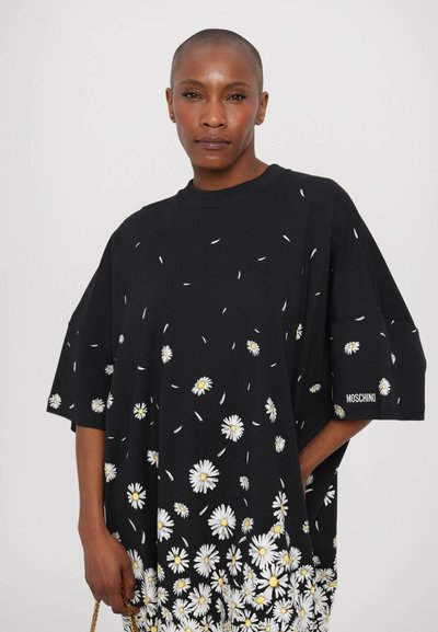 Oversized sort t-shirt lavet af bomuld, med hvide margueritter og gule midter. Logotype "Moschino" på ærmet. Korte ærmer, afslappet pasform.