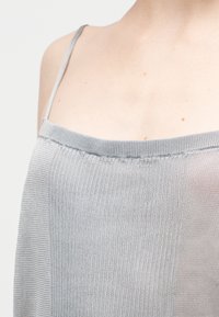 Γκρι ριμπ τοπ με στενούς ρυθμιζόμενους ιμάντες και ίσια γραμμή λαιμού, με μαλακή υφή και ελαφρύ ύφασμα.