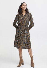 Hemdblusenkleid mit mehrfarbigem Druck in Braun-, Blau- und Creme-Tönen. Lange Ärmel, durchgehende Knopfleiste, taillierter Schnitt und knielanger Saum.