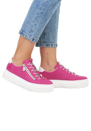 Pink suede sneakers with white rubber sole, featuring decorative zipper and eye-catching hardware accents. Paired with cropped denim jeans.