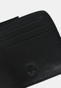 Portafoglio in pelle nera con più slot per carte e una finitura testurizzata. Presenta un delicato dettaglio del logo embossato. Forma rettangolare compatta.