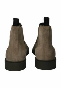 Par de botines cortos de ante beige con tiradores negros y paneles laterales elásticos, mostrados desde la parte posterior sobre un fondo blanco.