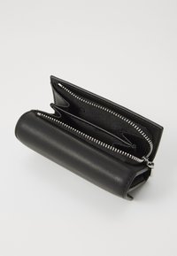 Schwarze Lederbörse mit zylindrischer Form, ausgestattet mit einem Reißverschluss, mehreren Fächern und einer strukturierten Oberfläche.