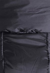 Schwarze gepolsterte Jacke mit einer glatten, matten Textur. Rechteckige Form, die über gesteppten Bereichen und ein einfaches, minimalistisches Design verfügt.