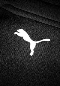 Tejido negro con un logo de puma blanco en salto. La textura parece suave y ligeramente brillante; el diseño es minimalista y audaz.