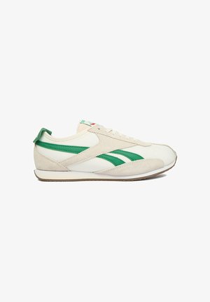 Witte en beige lage sneaker met groene strepen, vetersluiting en zool van kauwgomrubber, zijaanzicht tegen een witte achtergrond.