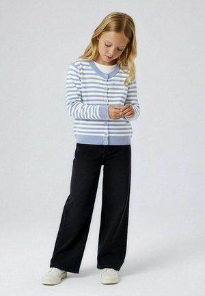 Pruhovaný svetr na knoflíky v světle modré a bílé barvě, s kulatým výstřihem. Kombinován s černými džínami s širokými nohavicemi a bílými teniskami.