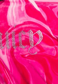 Rosa sammetstyg med ett marmorliknande mönster och glänsande rhinestone-texter som staver "Juicy." Mjuk textur, livlig färg och framträdande designelement.