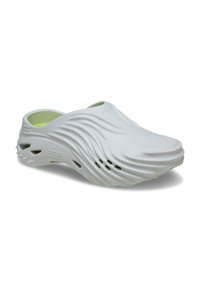 Sabots Crocs blancs avec une texture ondulée et un design découpé. L'intérieur est rehaussé d'une touche de vert. Fabriqués en matériau léger. Dos fermé.