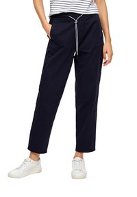 Pantalon en coton bleu marine avec une coupe décontractée, doté d'une taille élastique et d'un cordon de serrage. Poches de chaque côté. Associé à des baskets blanches.