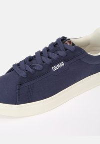 Baskets en toile navy avec semelle en caoutchouc blanc, dotées d'un design à lacets, d'un bout rond et du logo "COLMAR" sur le côté.