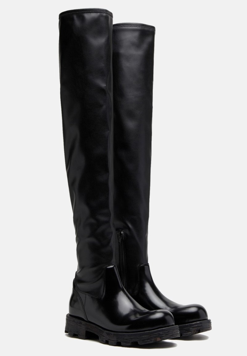 Botas negras por encima de la rodilla hechas de material sintético brillante, con una suela de goma resistente y un detalle de cremallera lateral para ponerlas y quitarlas fácilmente.